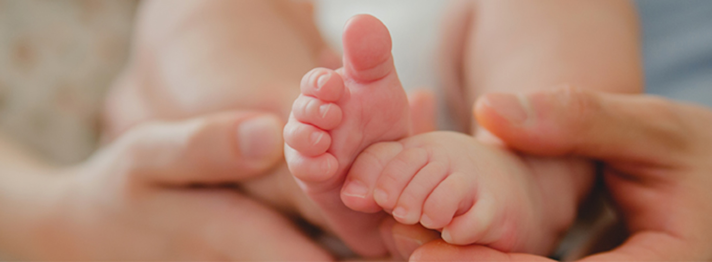 close up of adult hands holding small baby feet